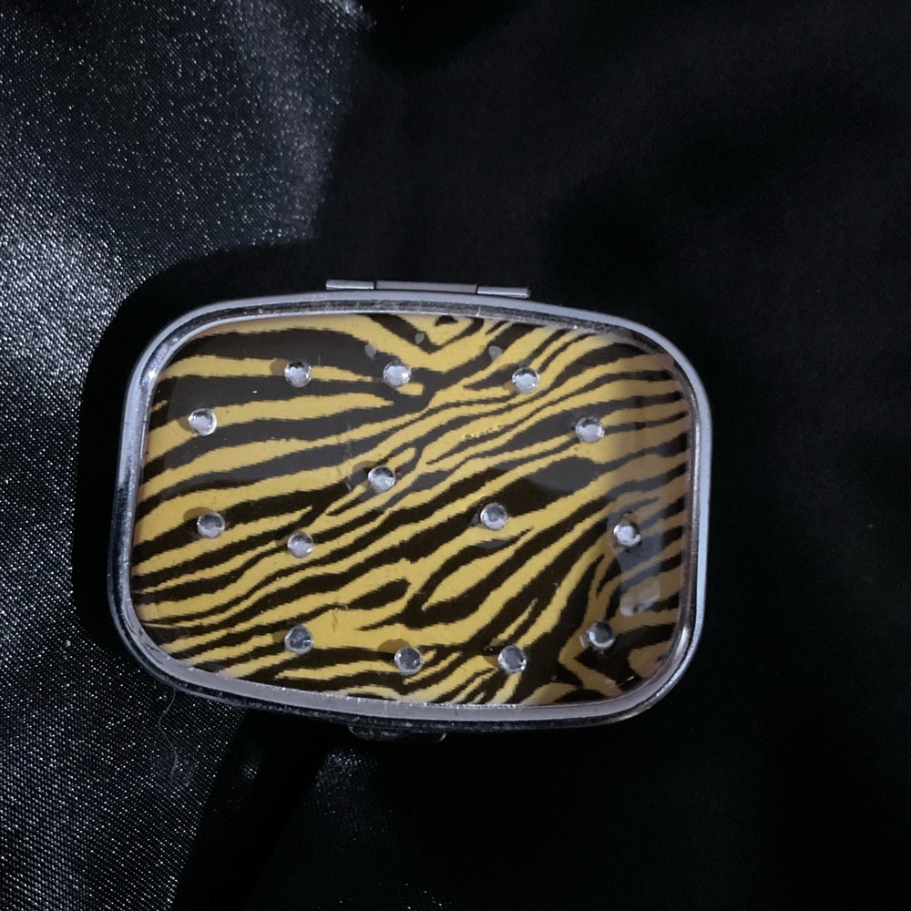 A compact, zebra patterned pill case or travel medicine organizer 1314